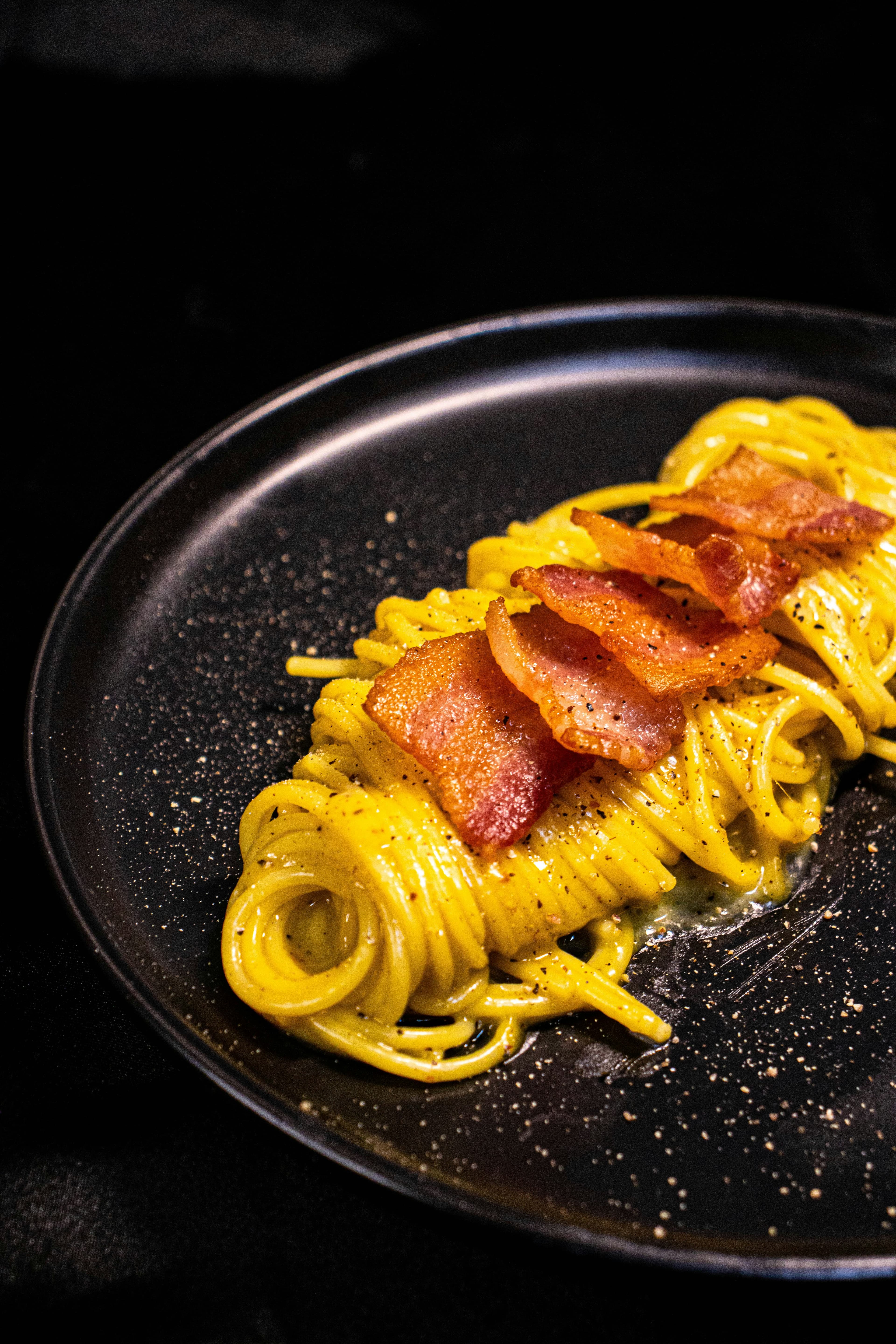 Dark-plate pasta with cracked pepper